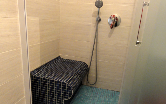 Un banc en Wedi recouvert de mosaïque permet à une personne à mobilité réduite de s'asseoir dans la douche, 80 x 170 cm.