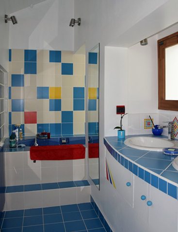 Au dessus de la baignoire: un damier mural en faïence bleue avec des touches rouge et jaune, réalisé par-P-Olivier
