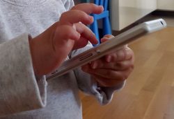 Mains d'enfant tapant sur le clavier d'un smartphone